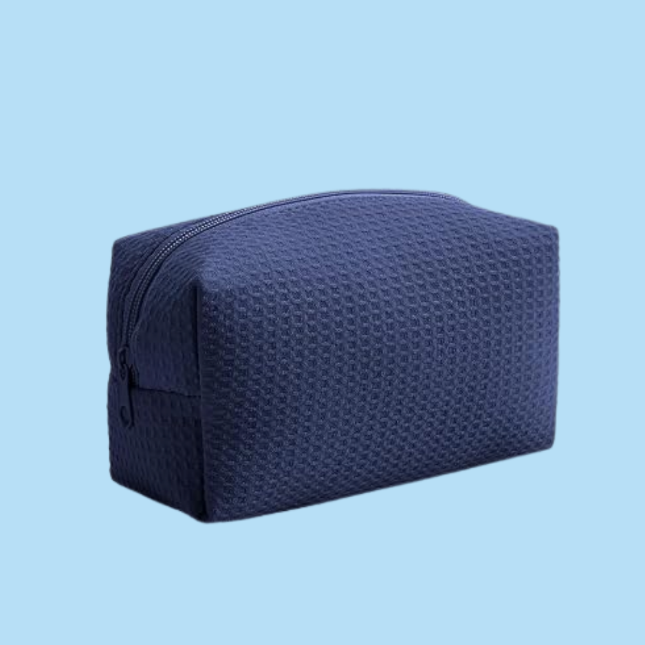 A navy blue textured zippered pouch bag, shown from a three-quarters angle against a solid light blue background.