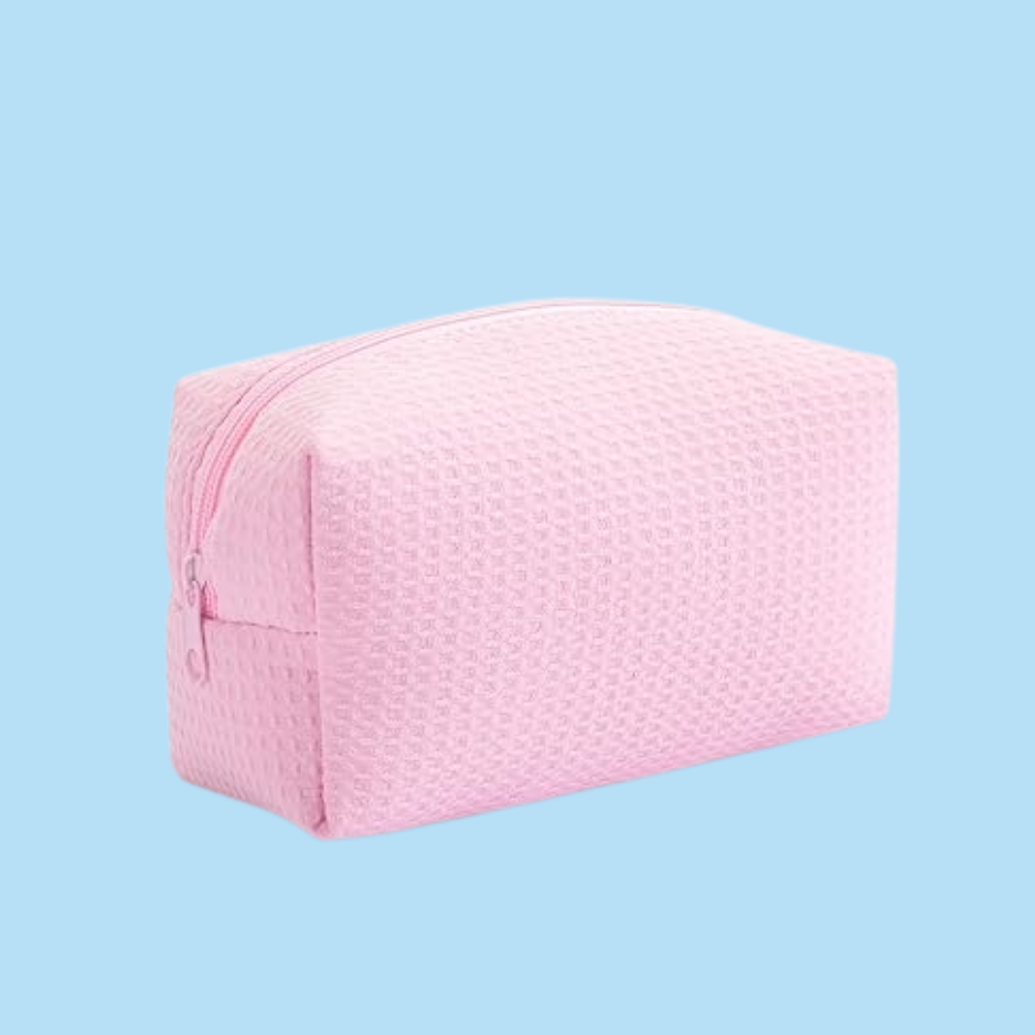 A light pink textured zippered cosmetic pouch shown on a solid light blue background.