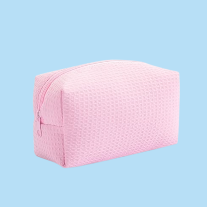 A light pink textured zippered cosmetic pouch shown on a solid light blue background.